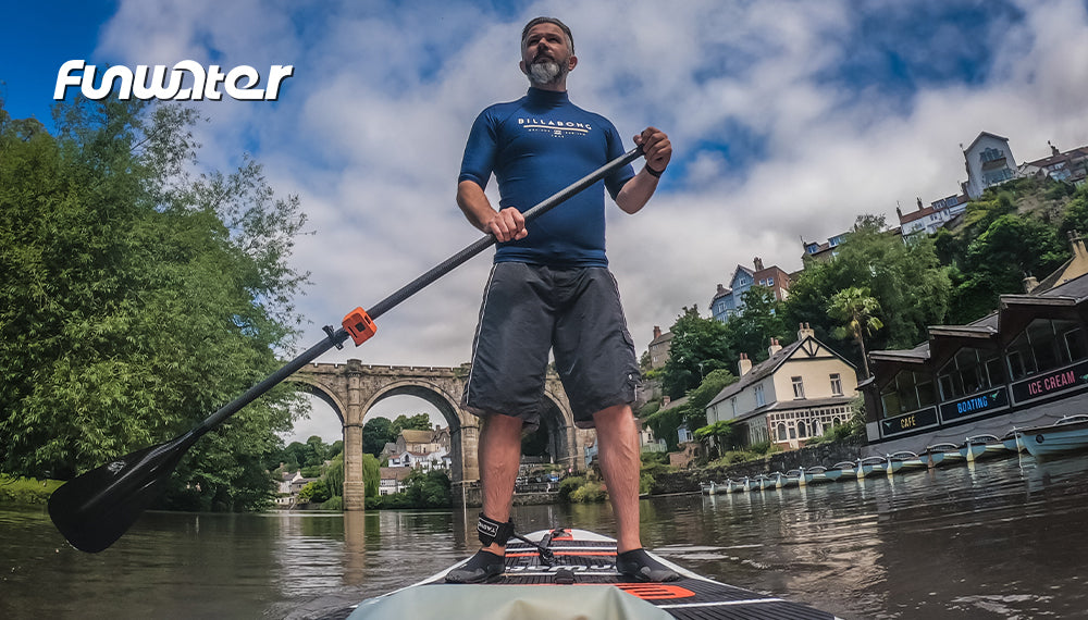 A man is paddling a FUNWATER paddle board